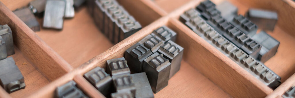 close-up of type slugs (individual letters used for printing) in wooden storage tray
