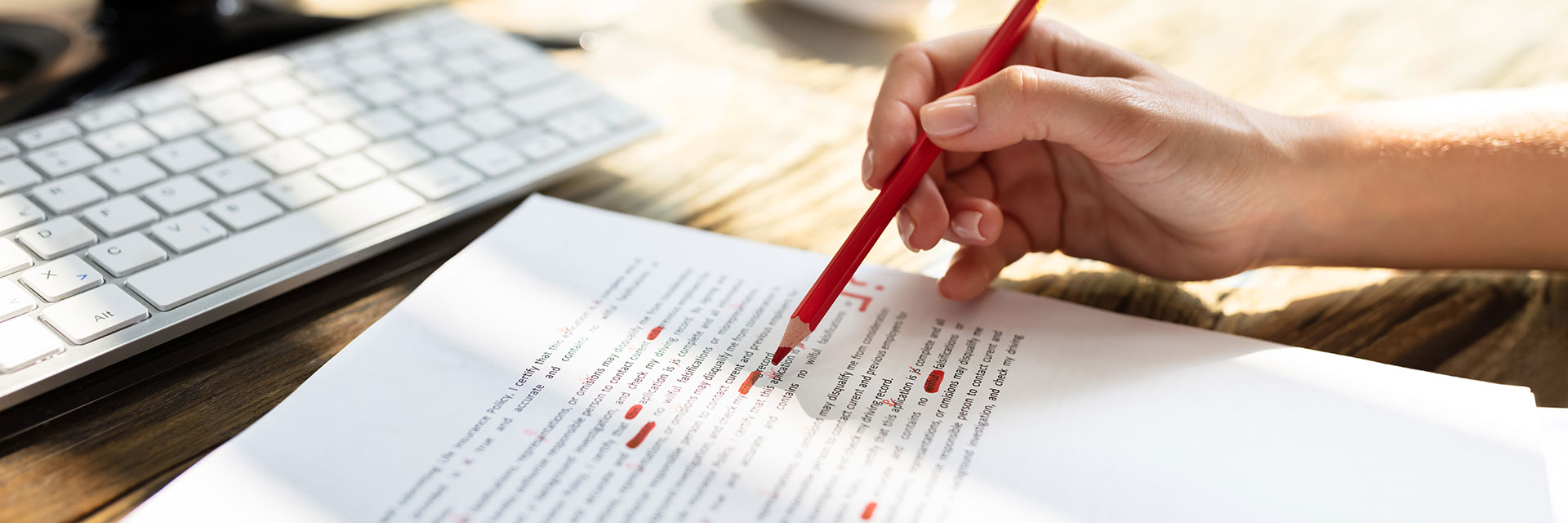 closeup of editor's hand marking up a manuscript in red pen